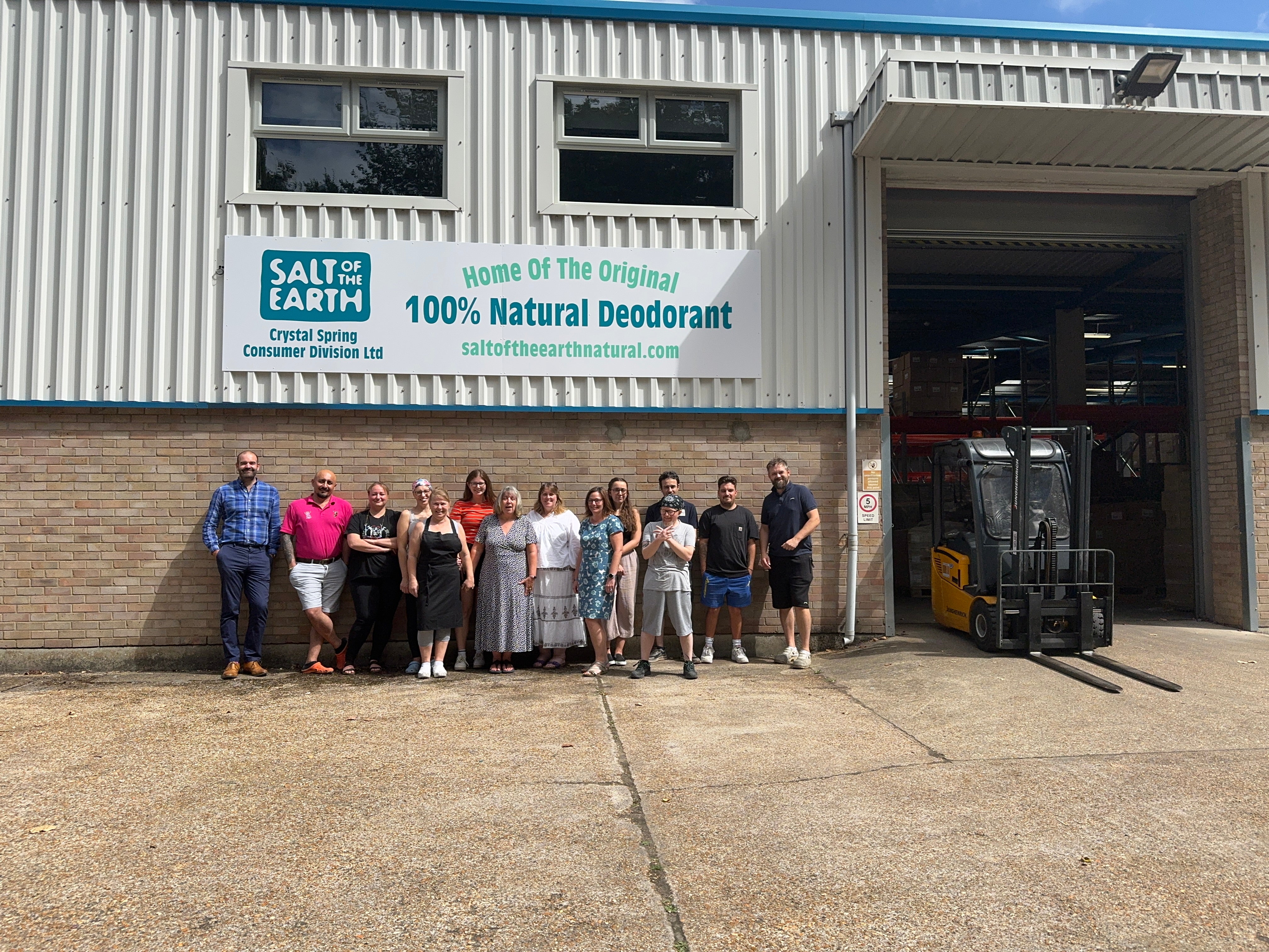 Salt of the Earth team standing proudly outside their warehouse, showcasing teamwork and authenticity in a spontaneous, unedited group photo in front of a roll shutter door.