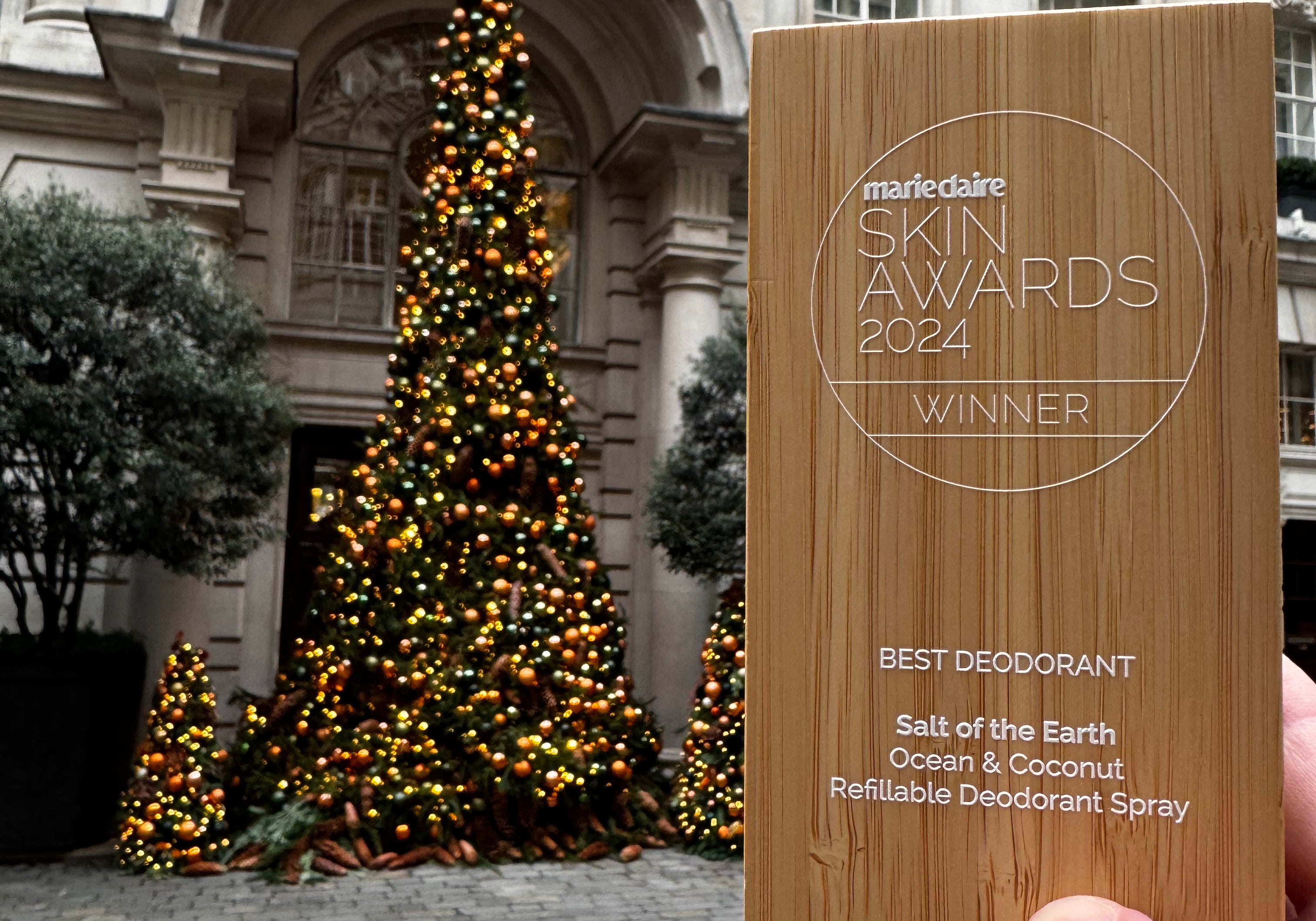 Marie Claire Beauty Award 2024 held against a decorated Christmas tree, celebrating Ocean & Coconut Spray Deodorant's win