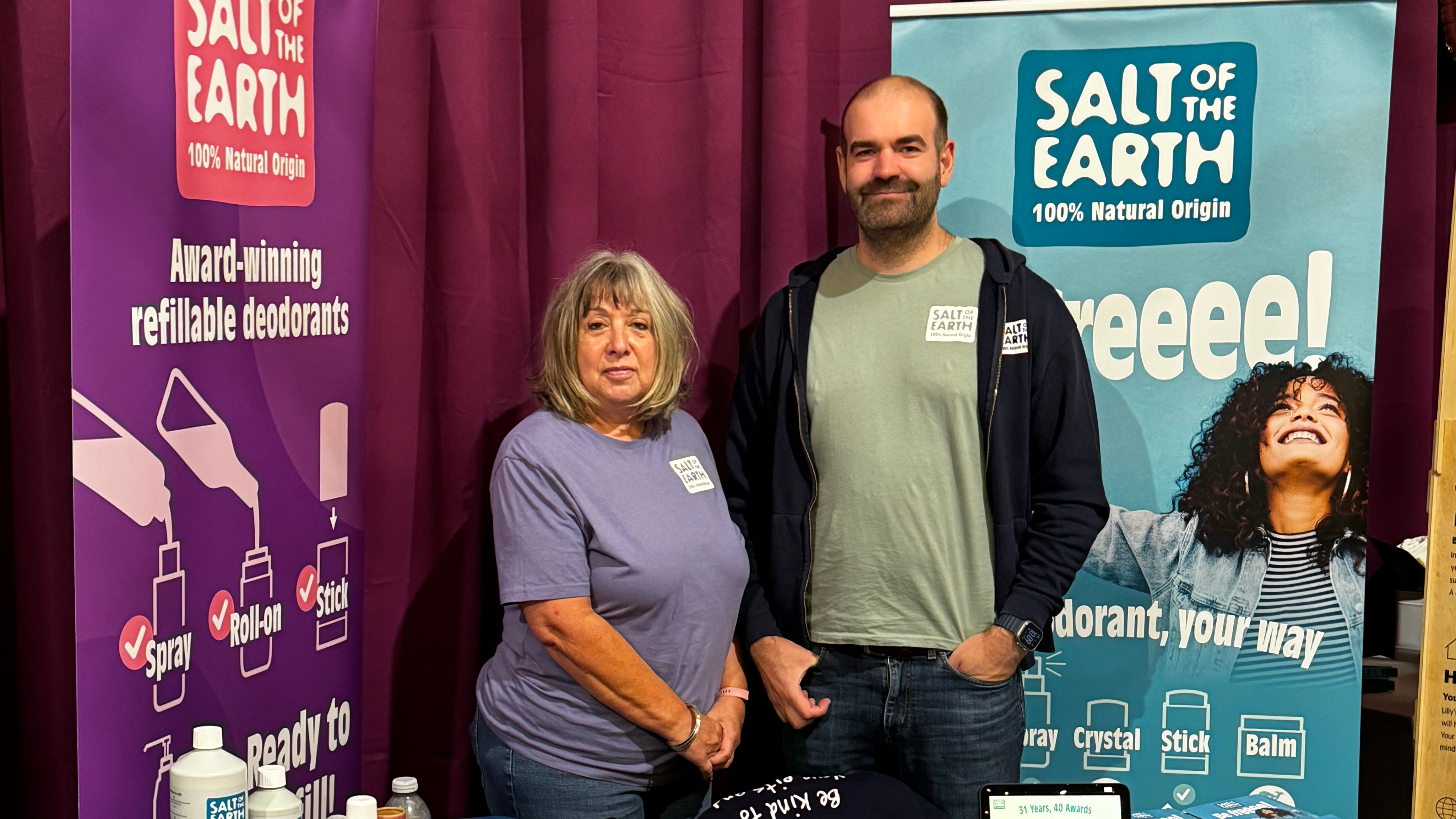 Thomas and Sara standing behind the Salt of the Earth stand at the Wholefoods Wholesale Supplier Summit 2024, showcasing natural deodorants at the scent station.