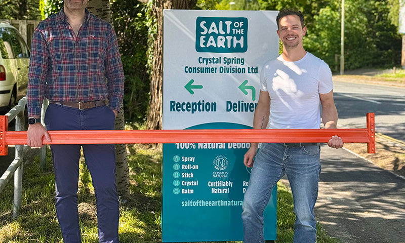 Thomas from Salt of the Earth and Brett Sanders from The Natural Deodorant Co. standing together outside the Salt of the Earth warehouse in Hampshire, holding orange warehouse racking equipment during their collaboration visit